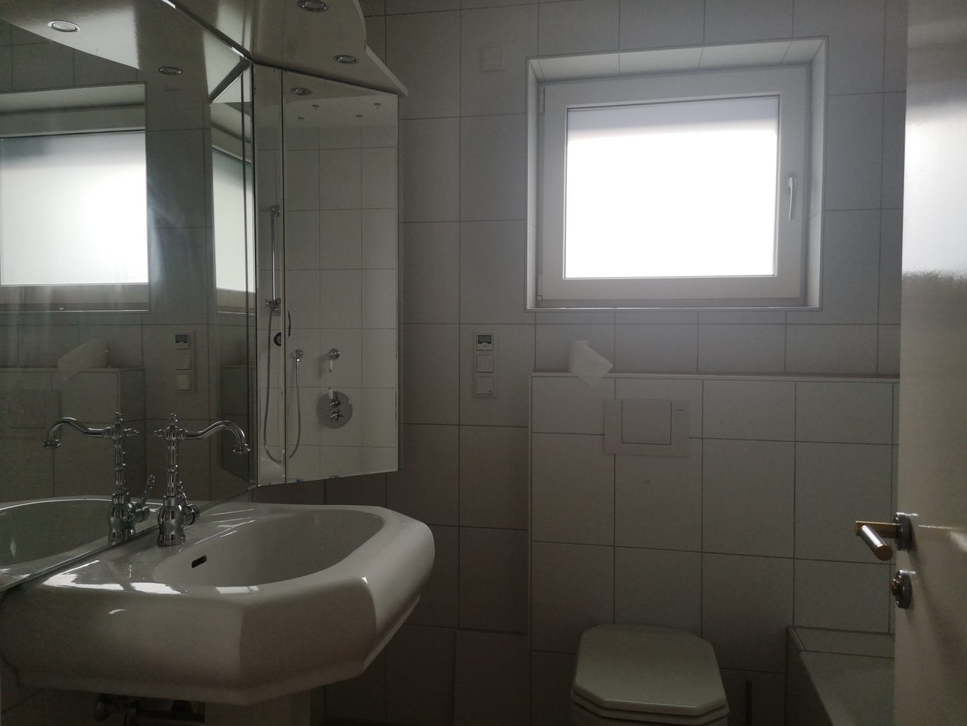 Homestaging Helles Badezimmer mit Waschbecken, Toilette und Fenster. Weiße Fliesen.