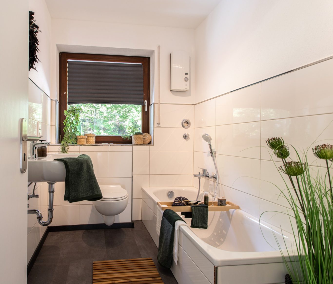 Immobilienmakler Münster Modernes Badezimmer mit Badewanne, Dusche und Pflanzen auf dem Fensterbrett.