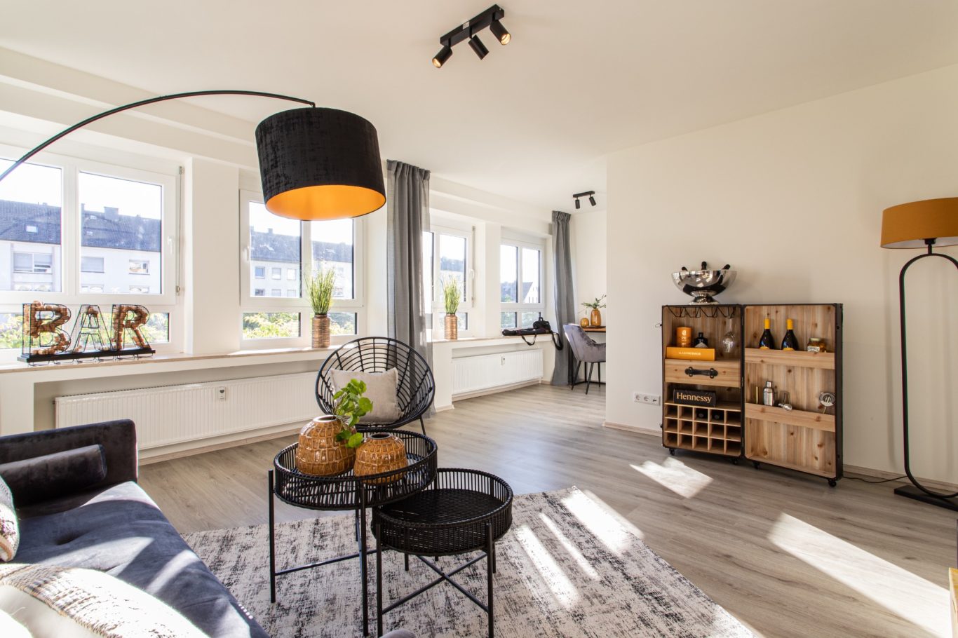 Immobilienmakler Münster Heller Wohnraum mit modernen Möbeln, einer Stehlampe und einem Korbstuhl.