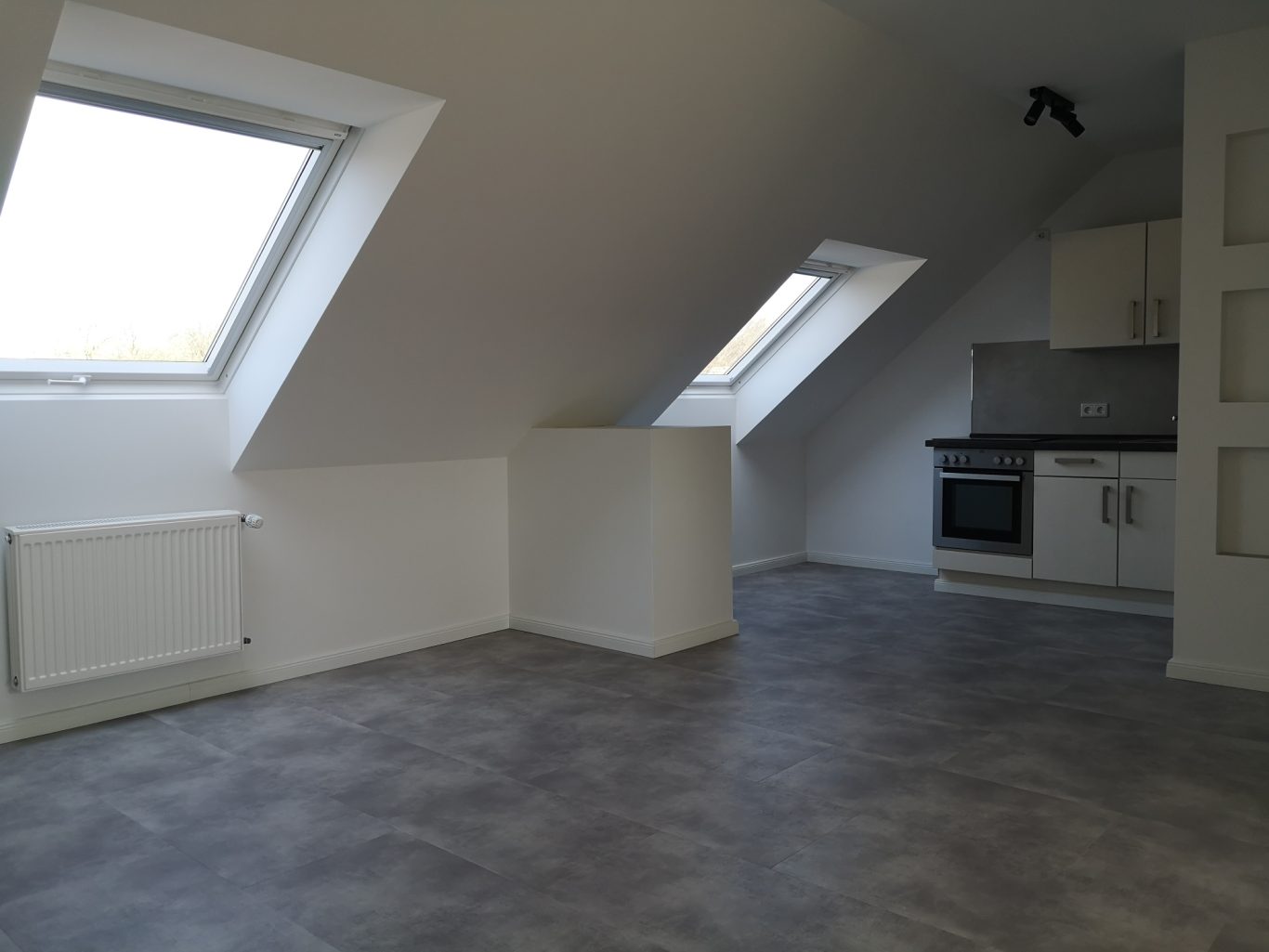 Immobilienmakler Münster Helle, moderne Dachgeschosswohnung mit Sicht auf die Küche und schrägen Wänden.