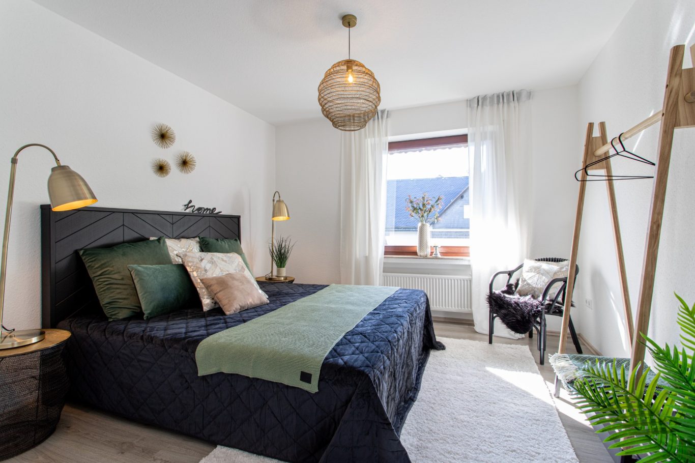 Immobilienmakler Münster Helles Schlafzimmer mit Doppelbett, gemütlicher Sitzgelegenheit und Pflanzen.