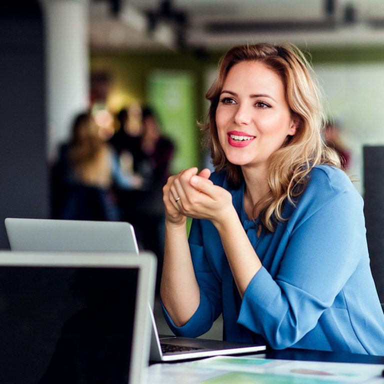 Lächelnde Immobilienmaklerin in Münster, die während eines Gesprächs sitzt.