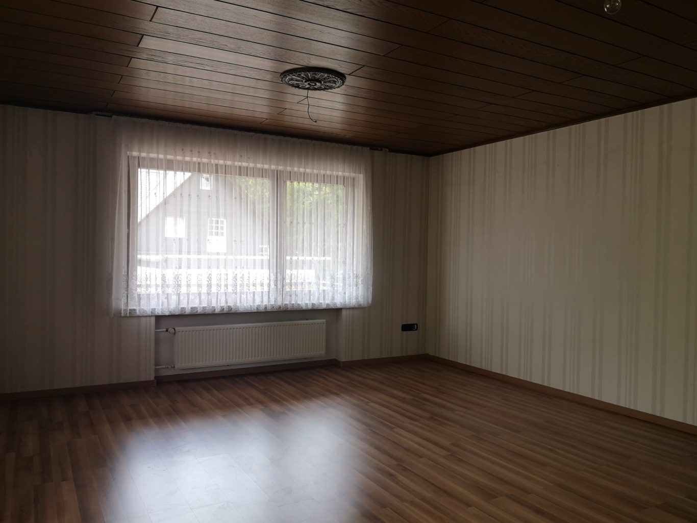 Immobilienmakler Münster Heller, leerer Raum mit Holzfußboden und großem Fenster.