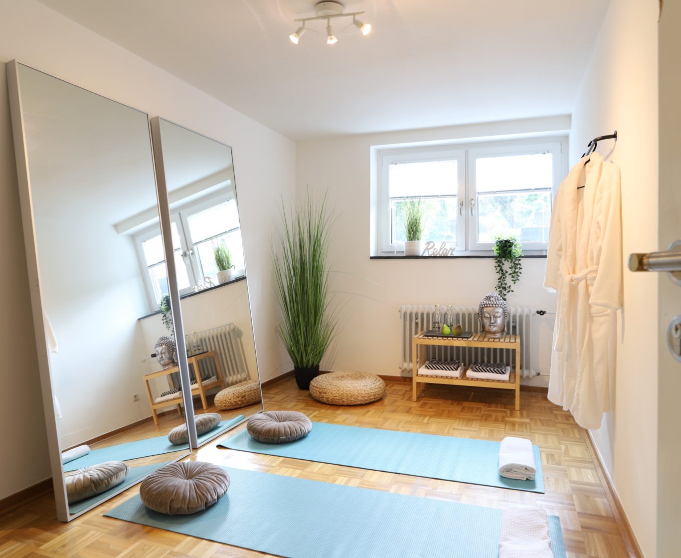 Haus kaufen Helle Yogastudio mit Spiegel, Matten, Pflanzen und entspannender Einrichtung.