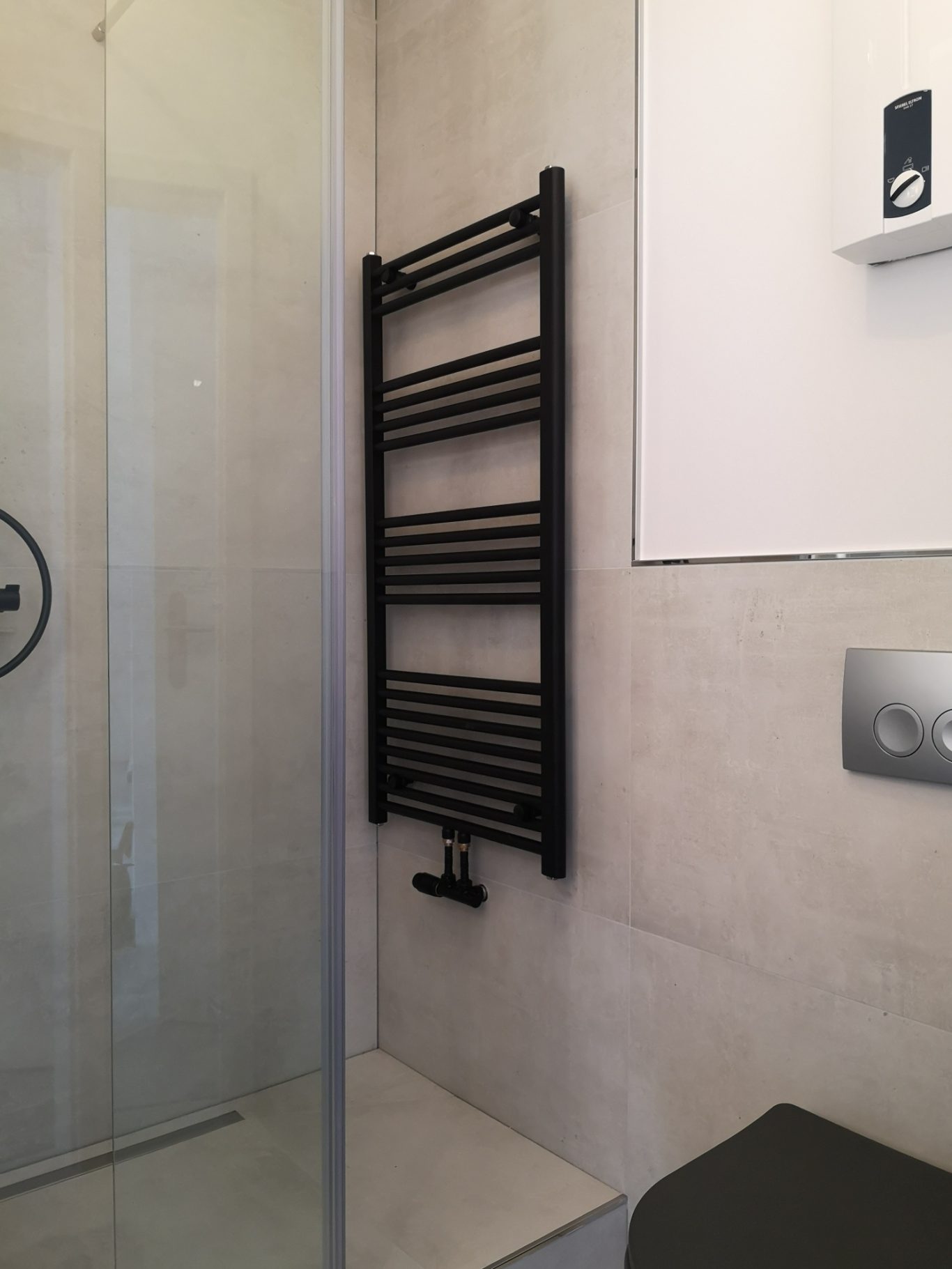 Immobilienmakler Münster Schwarzer Handtuchwärmer an der Wand in einem modernen Badezimmer.