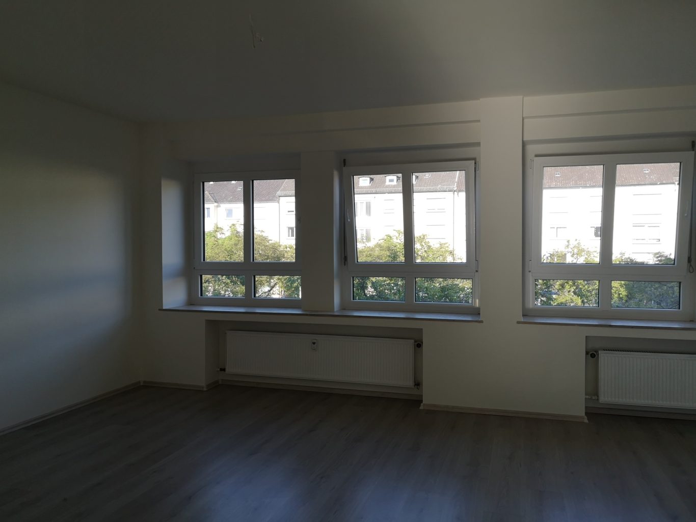 Preis Haus kaufen Münster Helle, leere Zimmer mit mehreren Fenstern und Blick ins Grüne.