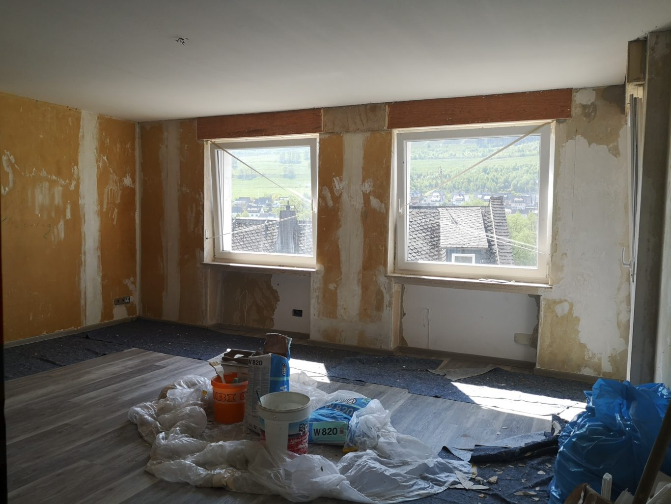 Immobilienmakler Münster Unfertiger Raum mit freiliegenden Wänden und Bauutensilien auf dem Boden.